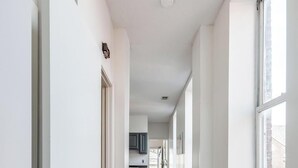 Un couloir doté d’un plancher en bois, de murs blancs et de grandes fenêtres.