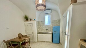 A compact kitchen with a dining table and chairs, a blue refrigerator, and a small window. - Corte Regi Appartment (Gallipoli)