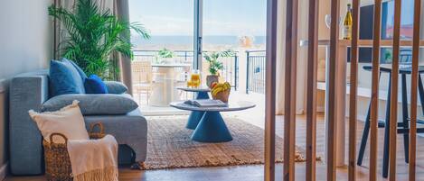 A modern living room with a grey sofa, a coffee table, and a balcony with a view.