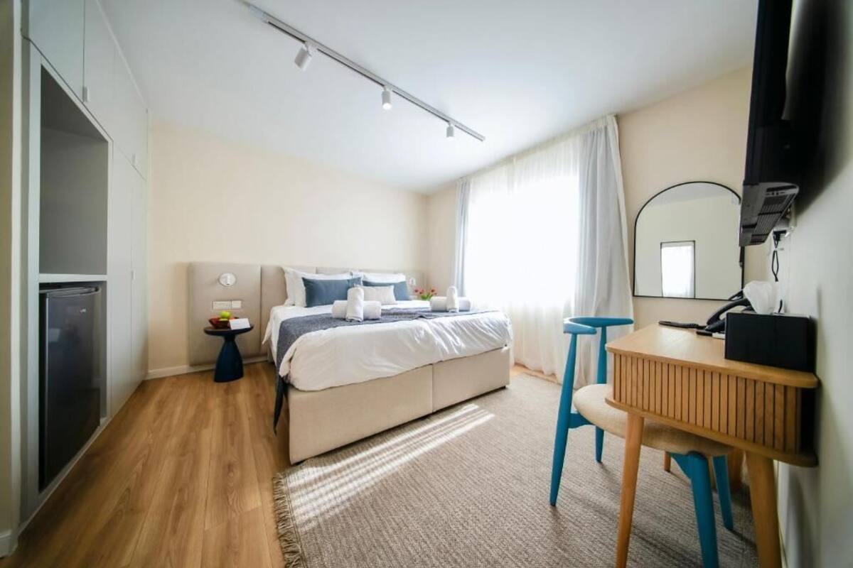 Um quarto com uma cama, mesa de cabeceira e escrivaninha com cadeira.