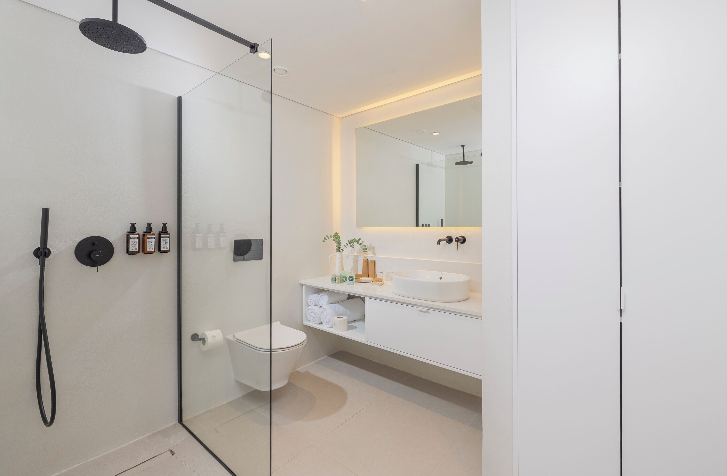 A modern bathroom with a glass-enclosed shower, a white sink, and a large mirror.
