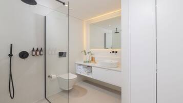 A modern bathroom with a glass-enclosed shower, a white sink, and a large mirror.