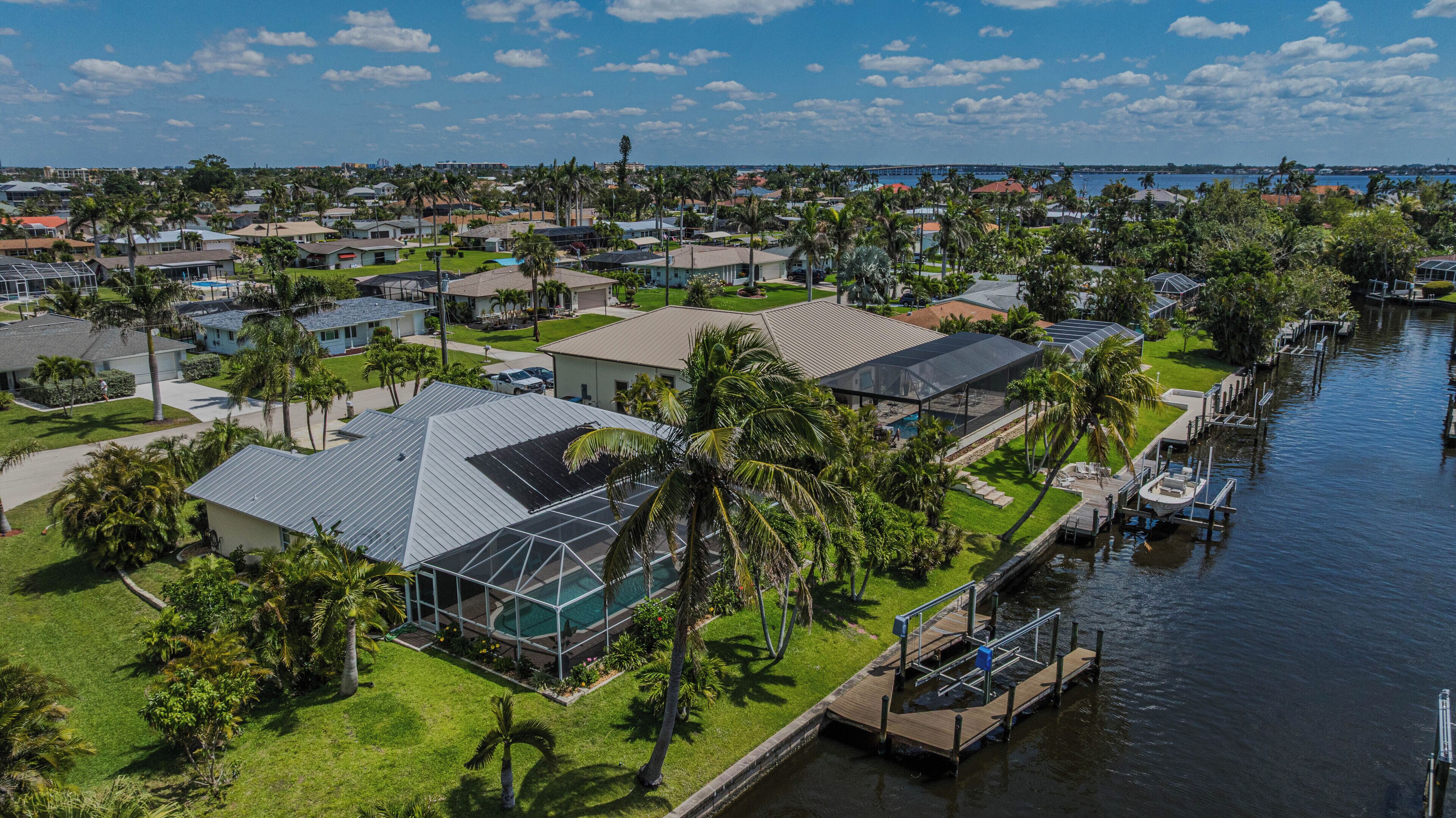 An aerial view of a residential area with houses, a dock, and a body of water.
