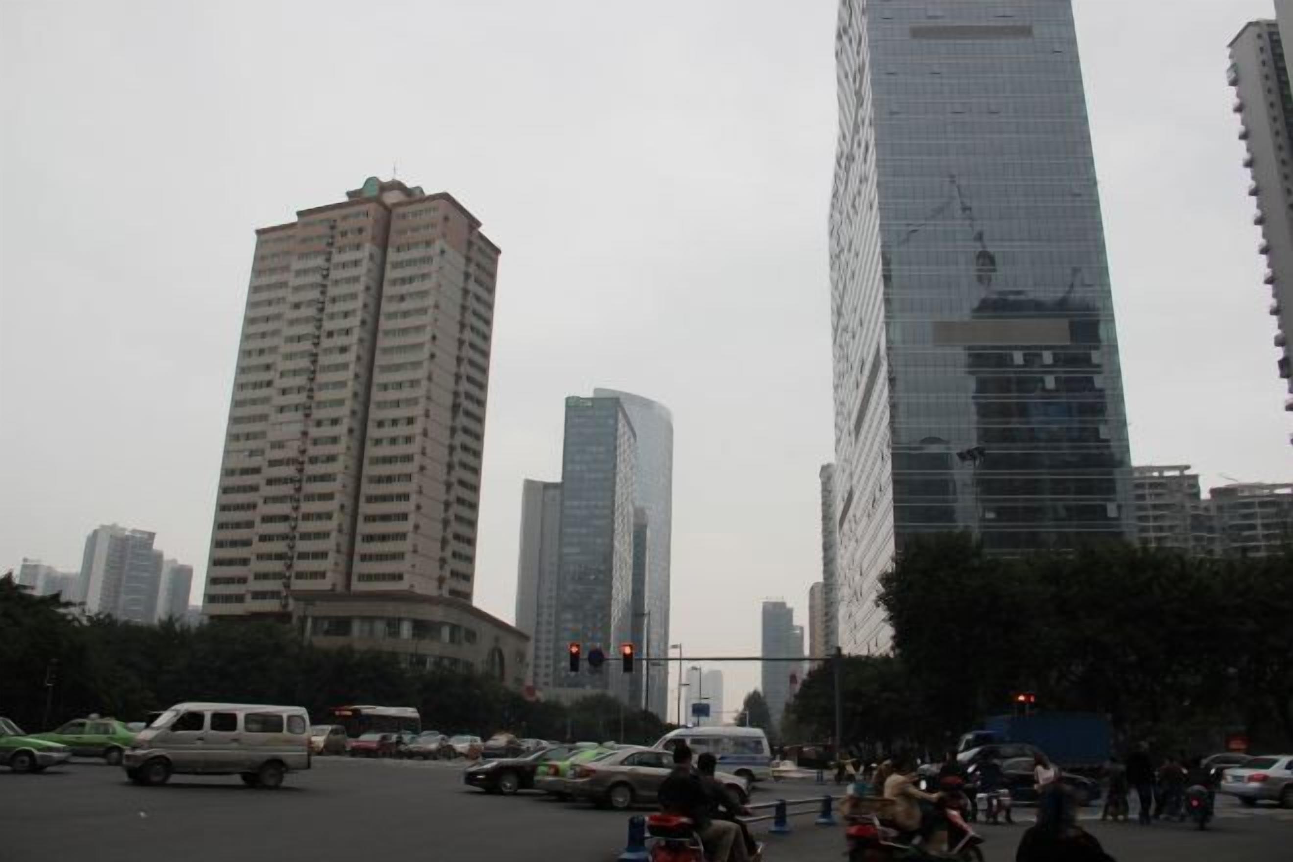 Un paisaje urbano con edificios altos, una intersección concurrida y vehículos.