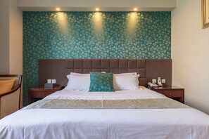A hotel room with a large bed, a headboard, two bedside tables, and a wall with a leafy pattern. - Shida Hotel (Chengdu)