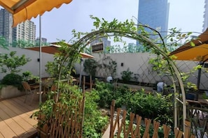 An outdoor patio area with a wooden fence, seating, and umbrellas. - Shida Hotel (Chengdu)