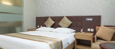 Una habitación de hotel con cama, mesitas de noche, un sofá y una pequeña mesa.