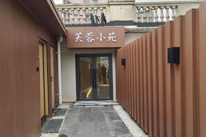 Entrada de hotel con un letrero, una puerta y un camino que lleva a la entrada.
