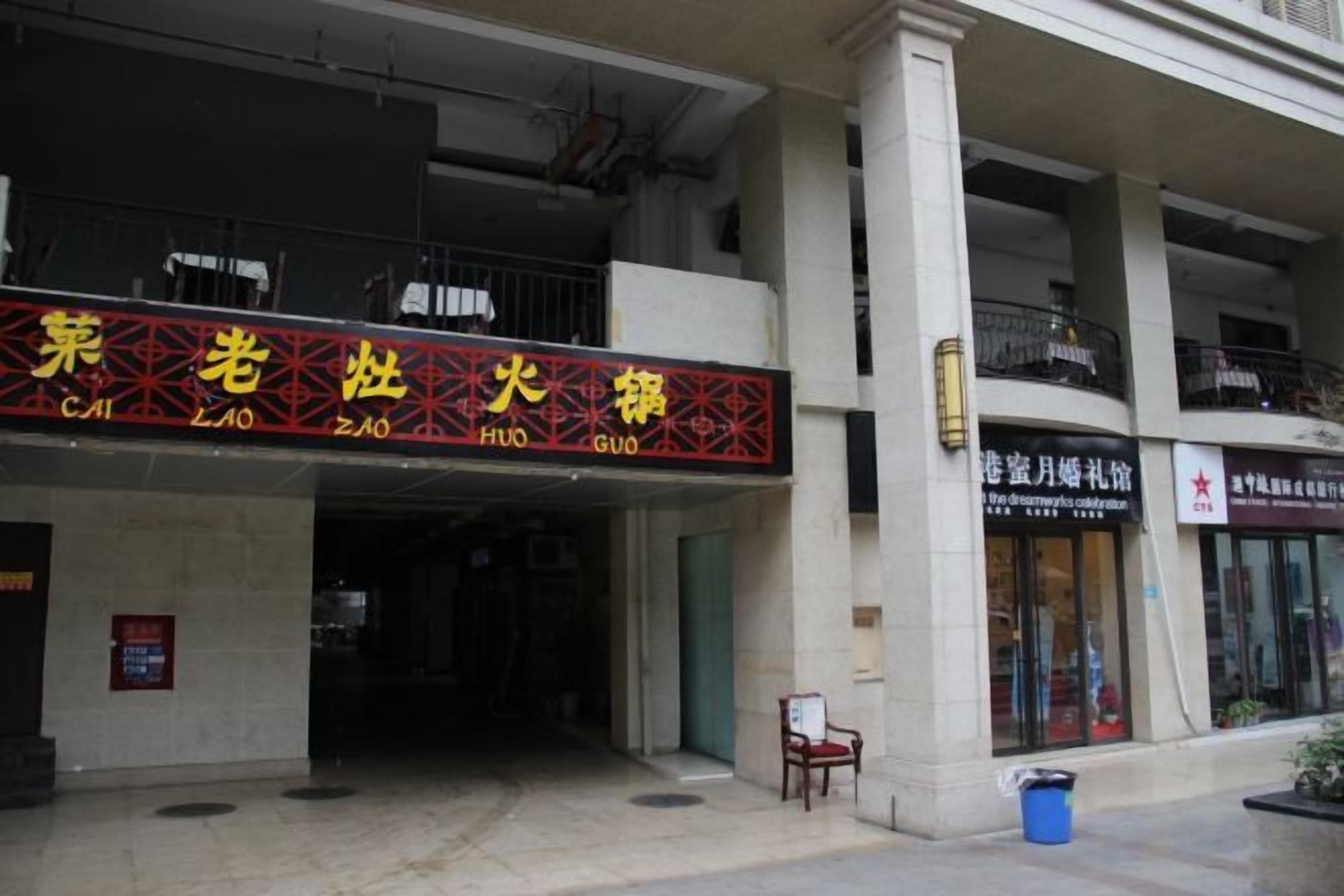 A building facade with a large sign in Chinese characters, a balcony, and a storefront with a red awning.