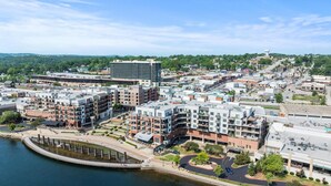 A waterfront urban area with modern buildings, a marina, and a pedestrian walkway. - UNIQUE CONTAINER HOME/Branson Landing/Trolley Stop/Gazebo (Branson)