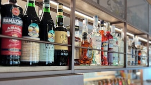 Estantes llenos de botellas de licores y copas de vino vacías.