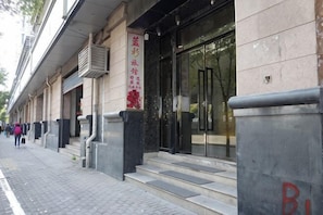 Un bâtiment doté d’une grande entrée en verre, d’un escalier menant à la porte et d’une enseigne rouge sur le mur.