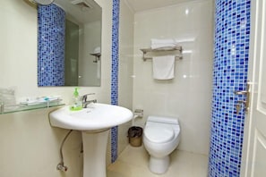 Une salle de bain avec un lavabo blanc, des toilettes et un miroir.