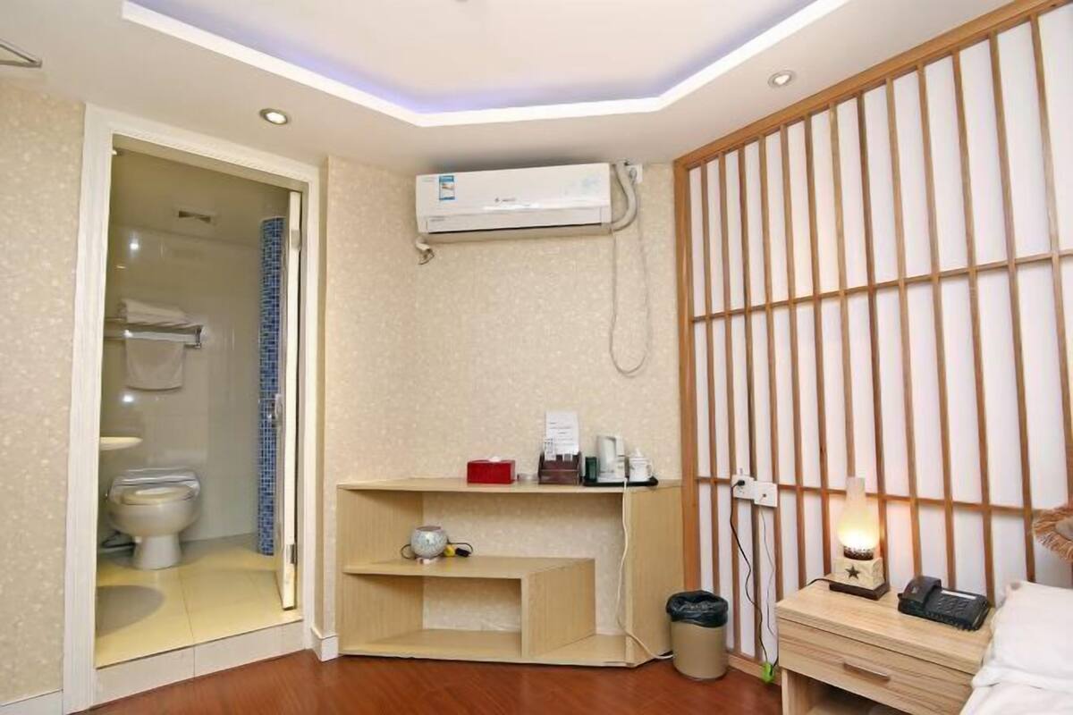 A modern bathroom with a toilet, shower, and an air conditioning unit.