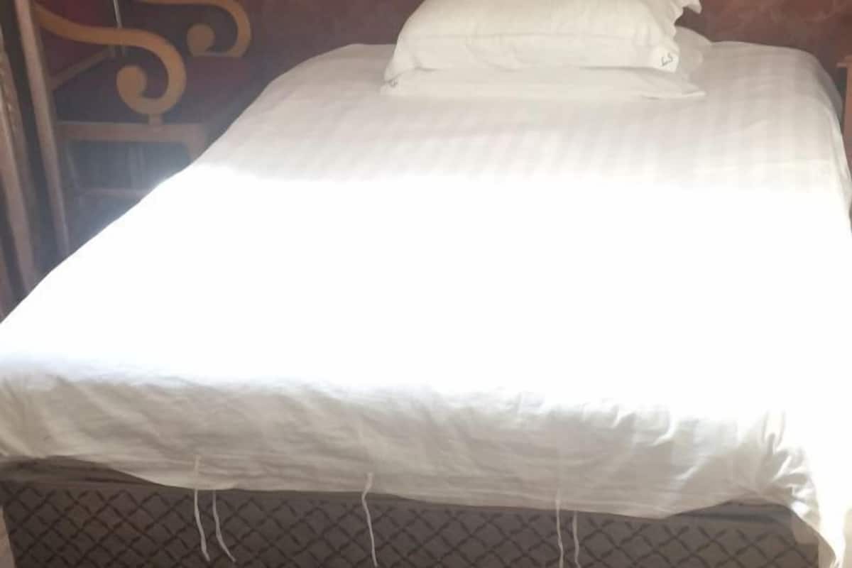 A bed with white bedding and a headboard with a decorative design.
