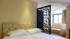 Un dormitorio con una cama grande, un separador decorativo, una ventana y un sofá.