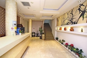 A hotel reception area with a reception desk, a staircase, and decorative shelves. - Lanshan Hostel (Shanghai)