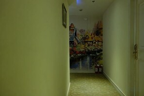 A hallway with a mural on the wall, a door on the right, and a framed picture on the left. - Lanshan Hostel (Shanghai)