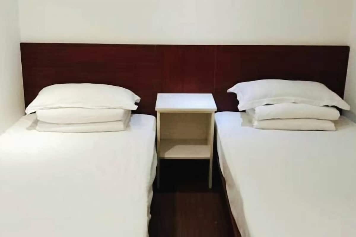 A twin room with two single beds, a small bedside table, and a headboard.