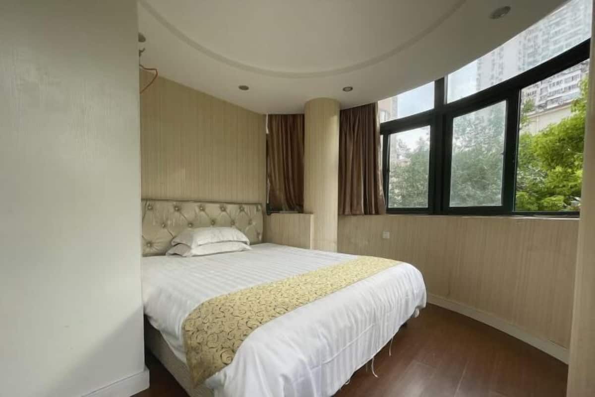 A bedroom with a large bed, a curved ceiling, and a window with a view of greenery.
