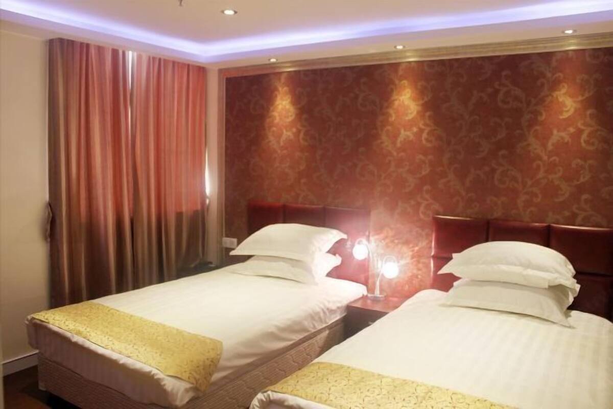 A hotel room with two beds, a red curtain, and a patterned wall.