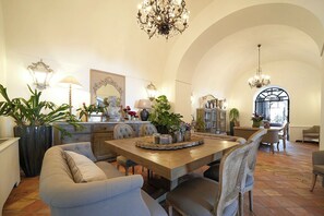 A spacious dining area with a high arched ceiling, a chandelier, and a variety of plants.