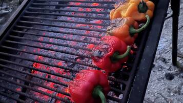 Ein Grill mit roten, orangen, gelben und grünen Paprika, die über offenem Feuer gegart werden.