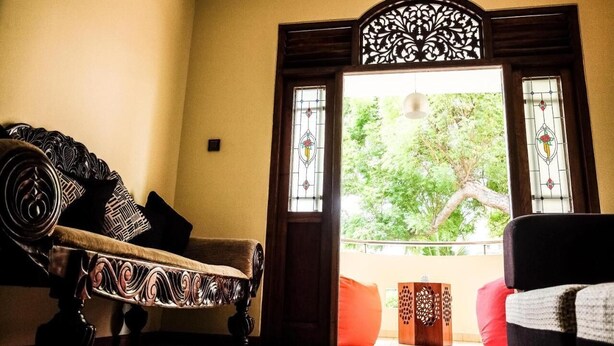 A room with a sofa, a chair, and a decorative wooden door with stained glass windows. - Vivid Colombo (Colombo)