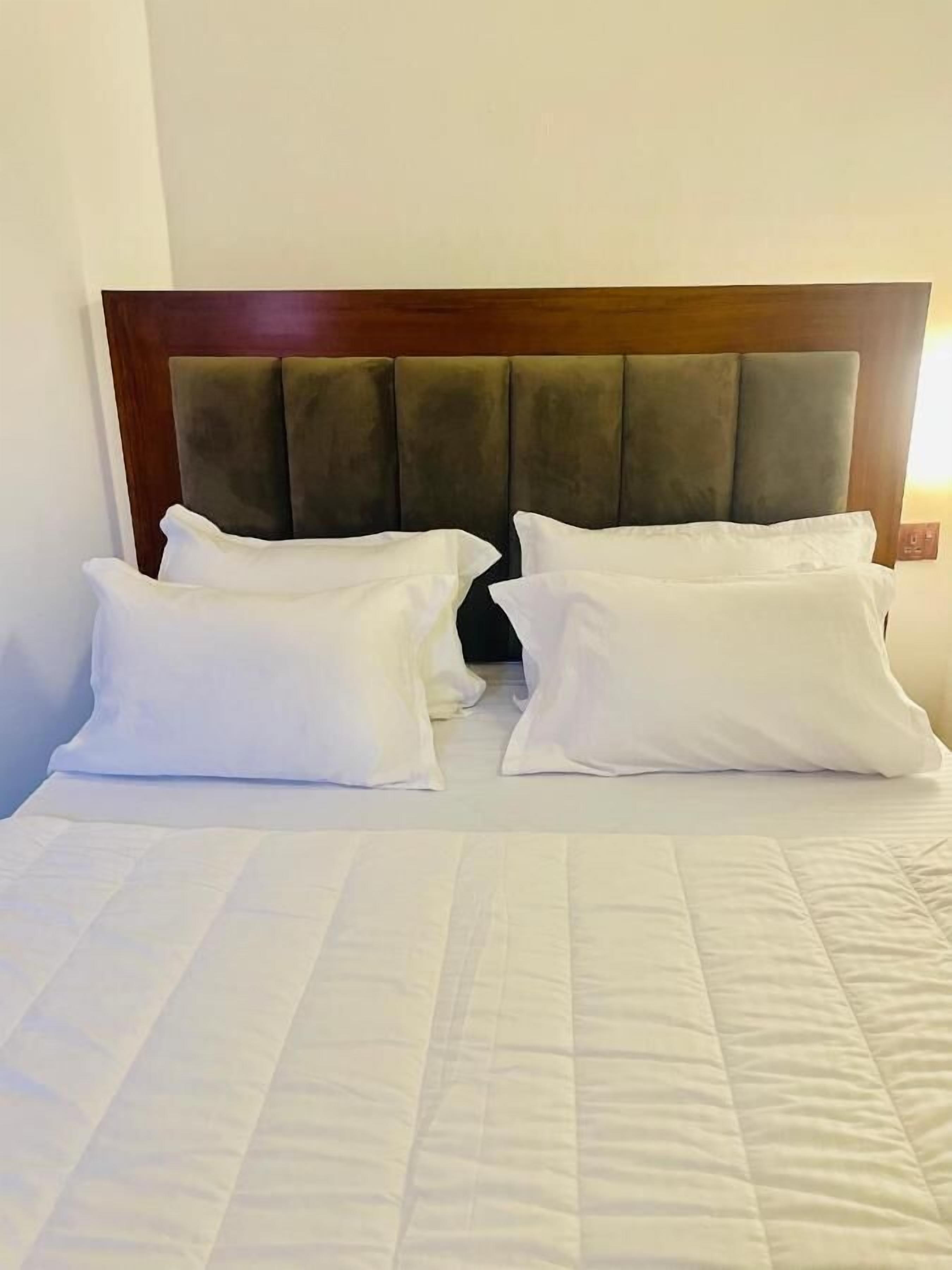 Une chambre d’hôtel avec un lit, deux oreillers blancs et une tête de lit en bois.