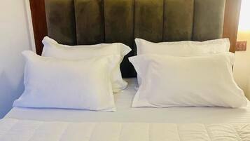 Une chambre d’hôtel avec un lit, deux oreillers blancs et une tête de lit en bois.