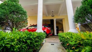 A red car parked under a white colonnade with a yellow wall in the background. - Vivid Colombo (Colombo)