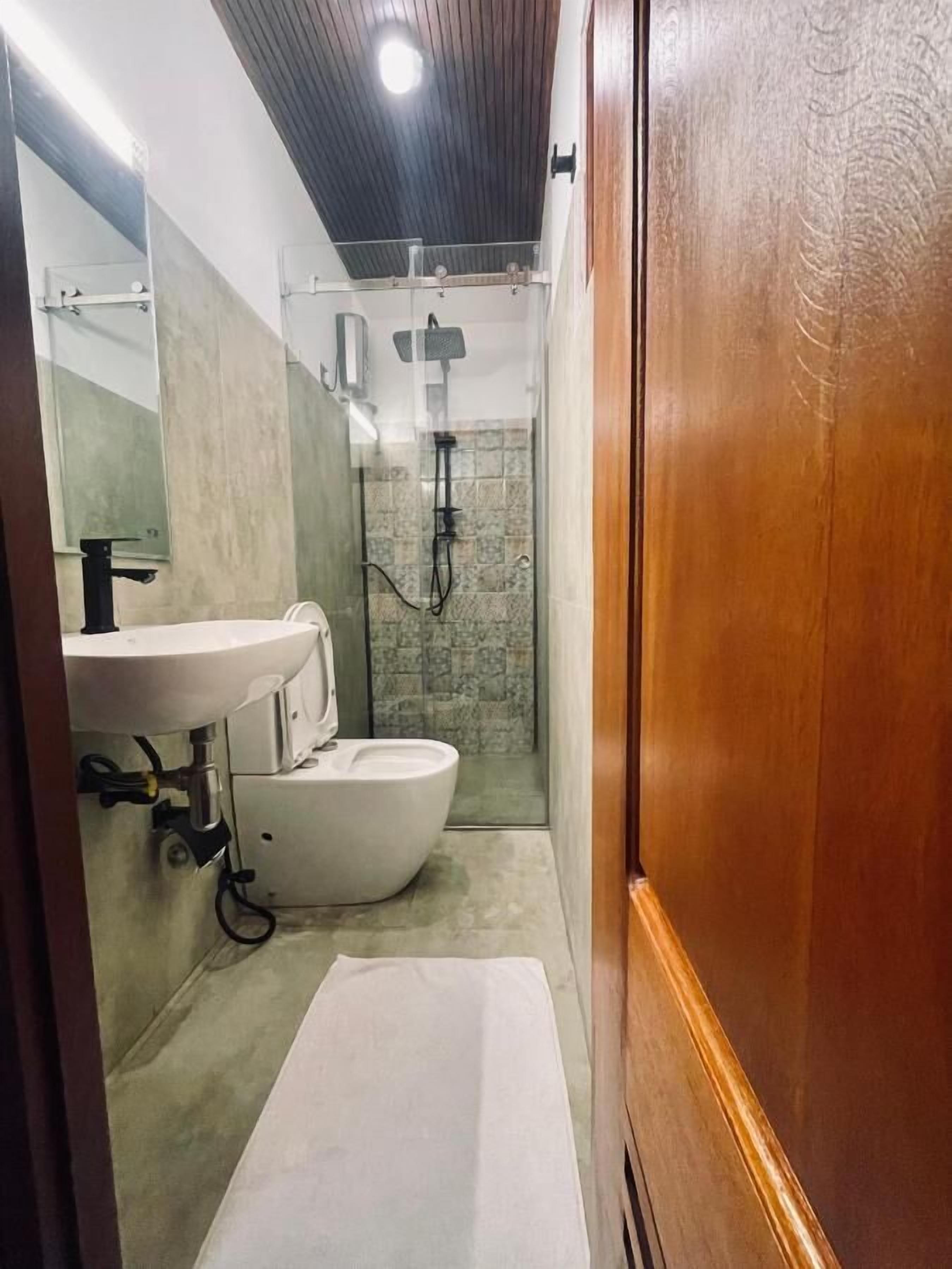 Une petite salle de bain avec un lavabo blanc, des toilettes et un espace douche.