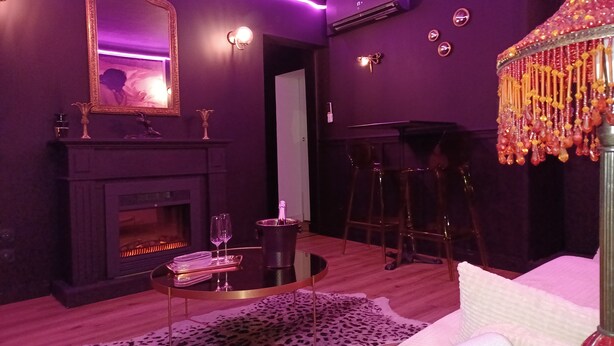 A room with a fireplace, a round table with a glass top, a leopard print rug, a white sofa, and a decorative lamp. - Love room - La Villa 1900 - L'Instant X - Chic cocoon for a night for two (Chérancé)
