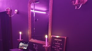 A room with a fireplace, a mirror, a sign with a welcome message, and a small table with a digital device and a candle. - Love room - La Villa 1900 - L'Instant X - Chic cocoon for a night for two (Chérancé)