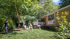 A backyard with a wooden deck, a covered seating area, and a small building. - ZEcamping 4 étoiles piscine chiens acceptés club enfant mobil-home BBQ (La Bastide-de-Sérou)