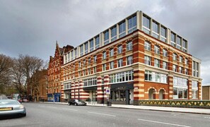 A multi-story building with a brick facade, large windows, and a corner entrance.