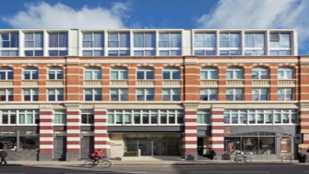 Un immeuble à plusieurs étages, doté d’une façade en briques et de grandes fenêtres.