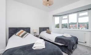 Une chambre d’hôtel avec deux lits, une grande fenêtre et une vue sur un bâtiment à l’extérieur.