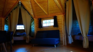 A cabin with a loft-style bedroom, a sofa bed, and a window with curtains.