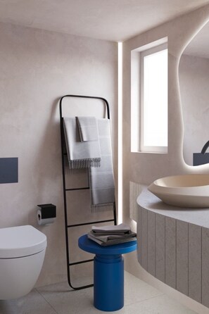 A modern bathroom with a white toilet, a blue trash bin, a towel rack with a towel, and a large sink with a mirror.