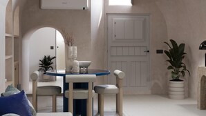 A modern interior with a round table, chairs, and a white door. - You & Me Cove Imerovigli (Imerovigli)