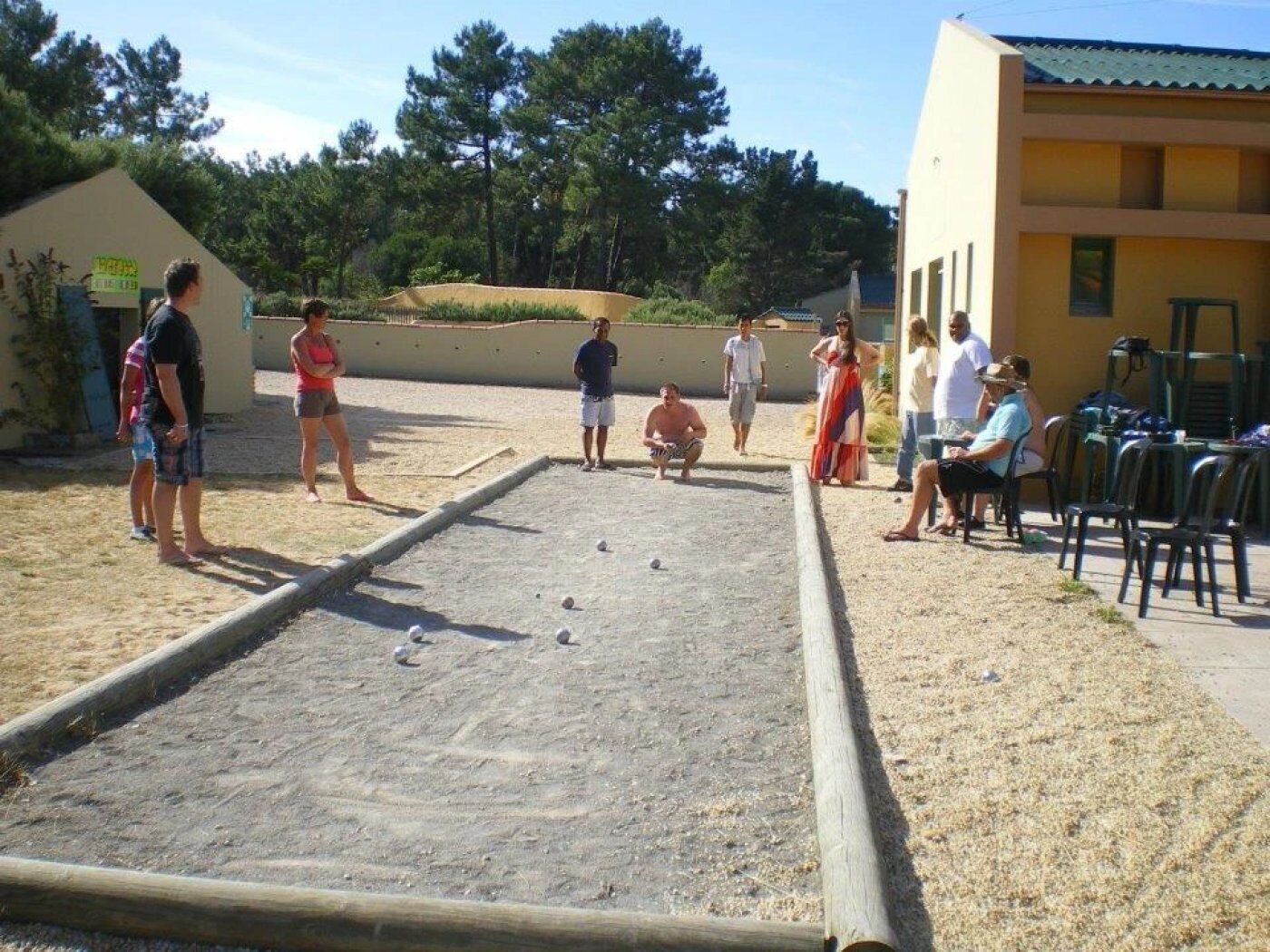 Ein Innenhof mit Shuffleboardtisch, Sitzgelegenheiten im Freien und einem Gebäude mit gelber Fassade.