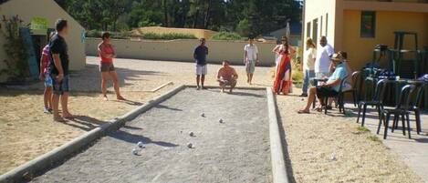Ein Innenhof mit Shuffleboardtisch, Sitzgelegenheiten im Freien und einem Gebäude mit gelber Fassade.