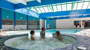Une piscine intérieure avec un sol carrelé, un plafond en verre et des murs bleus.