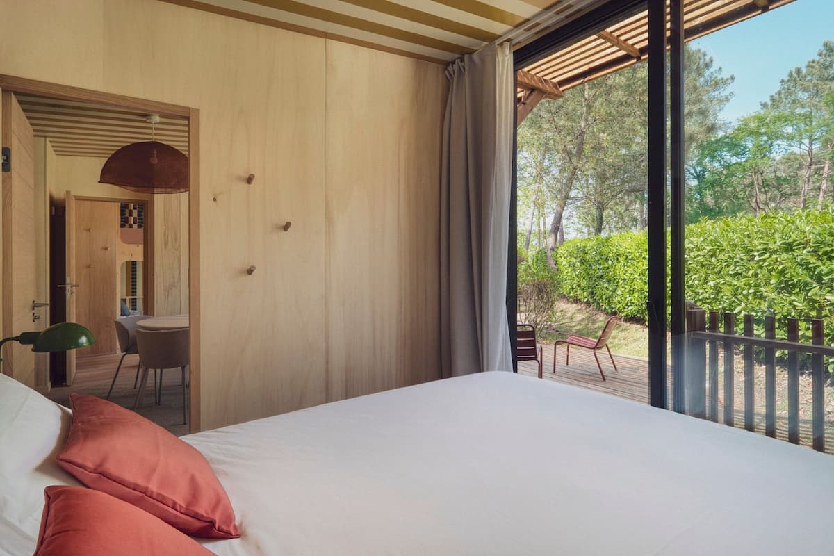 A bedroom with a bed, a desk, and a view of the outdoors.