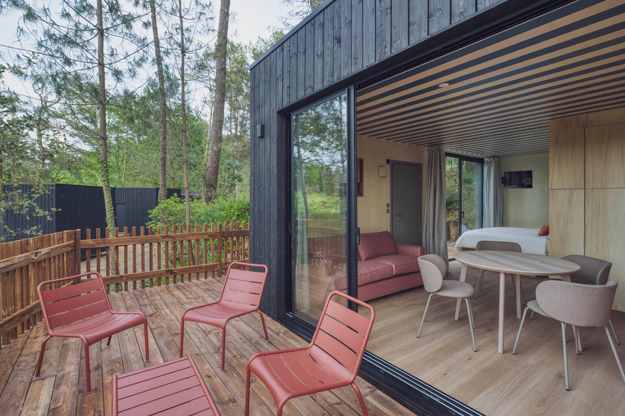 Eine moderne Terrassenausstattung mit Holzboden, Metallstühlen, einem runden Tisch und einer Sitzecke.
