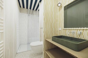 A bathroom with a white toilet, a shower with white tiles, and a green sink with a mirror above it. - BonjourSauvage Seignosse (Seignosse)