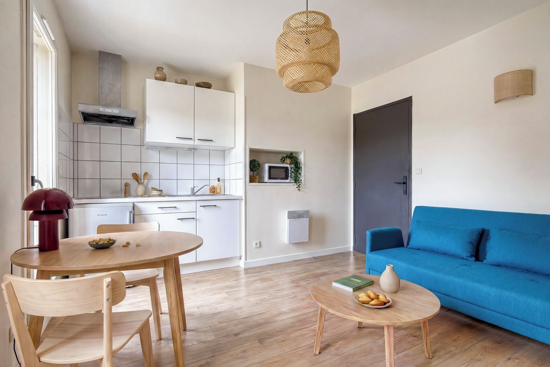 A modern living space with a kitchen, dining area, and a blue sofa.
