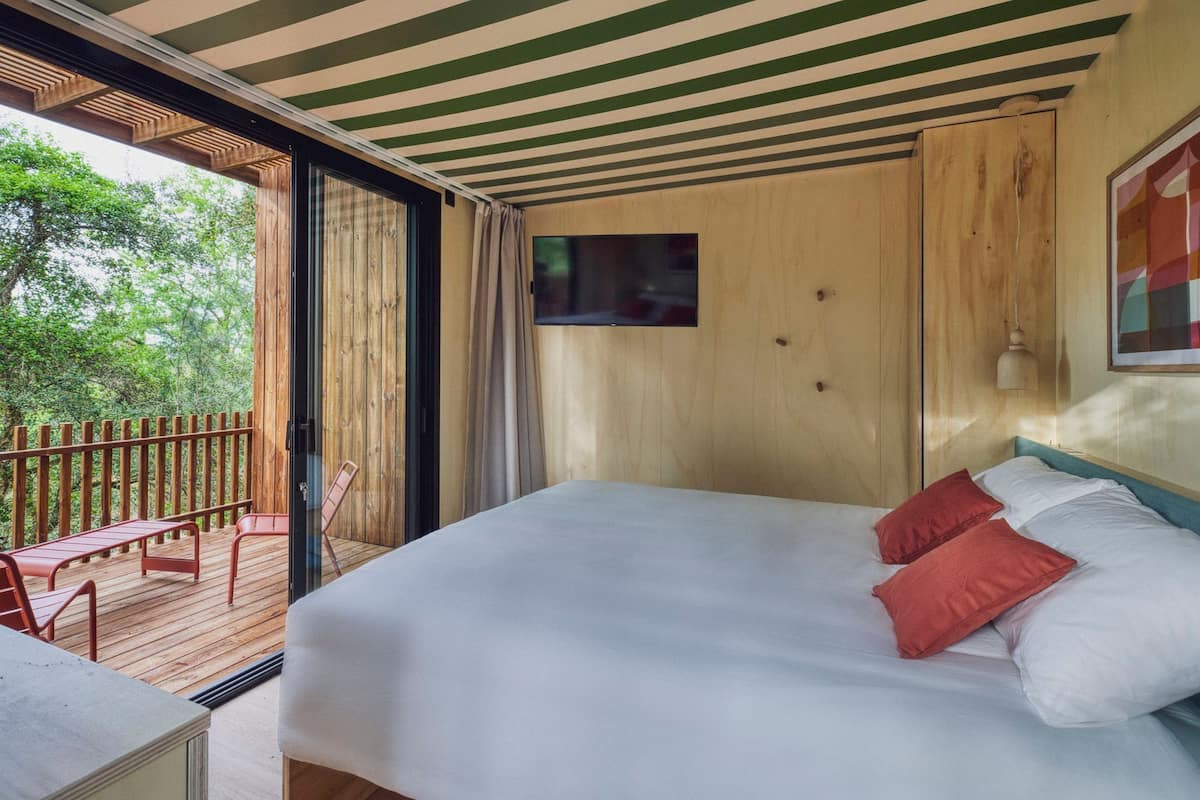 A bedroom with a bed, a TV, and a view of the outdoors.