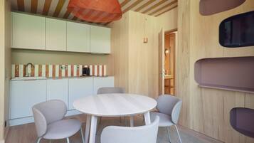 A modern kitchen with a round table and four chairs, wooden cabinets, and a striped backsplash.